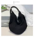 Dettaglio borsa shopper in maglia nera con tracolla in pelle regolabile su valigia - Nero
