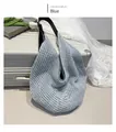 Dettaglio borsa da spiaggia in maglia blu con tracolla nera accanto a una valigia - Blu