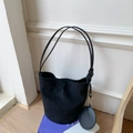 Detail of minimalist black suede bucket bag with long strap and detachable round coin purse - Black