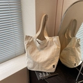 Minimalist beige nylon tote bag with large capacity and front pocket shown in home setting - Beige