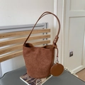 Detail view of brown suede bucket bag with a round coin purse and decorative knotted strap - Brown