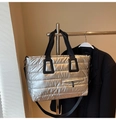 Detalle del bolso tote plateado acolchado con acabado metálico y correas de lona negra - Plateado