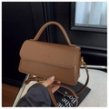 Close-up of brown matte leather shoulder bag showing the fine stitching and gold buckle - Brown