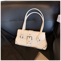 Close-up of cream leather shoulder bag with silver metal buckles and rivet details - White