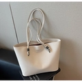Detail of cream leather tote with lychee texture and metallic hardware on black stand - White