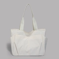 Detail view of a large cream tote bag showing dual front pockets and durable nylon fabric - White