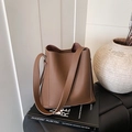Brown lychee texture bucket bag in a minimalist design placed on a book - Coffee