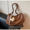 Detailansicht der braunen Vintage-Ledertasche mit Silberkette und süßem Bärenanhänger - Karamellbraun