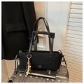 Dettaglio di borsa tote in pelle scamosciata nera con logo dorato e pendente in legno - Nero con ciondolo