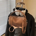 Vintage brown suede pillow bag with leather handles and silver buckles in hand - Brown