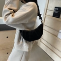 Borsa a mezzaluna nera chic con tracolla annodata e dettagli oro indossata da modella - Nero