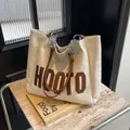 Detail einer großen cremefarbenen Ledershopper mit silberner Kette auf einer Steinoberfläche - Cremeweiß
