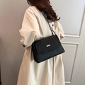 Schwarze Plissee-Tasche mit Silberschnalle und Kettenriemen über beigem Mantel - Schwarz