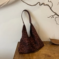 Bolso tote con estampado de leopardo y asas de cuero marrón sobre mesa de madera - Rojo