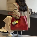 Red leather tote bag with green turtle plush charm shown in a model back view - Red with Pendant