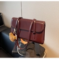 Detalle del bolso de hombro vintage rojo oscuro en cuero sintético con colgante de oso y costuras - Burdeos
