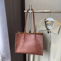 Vintage brown leather tote bag with distressed texture on a metal clothes rack - Brown No Pendant