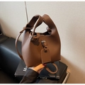 Détail du sac seau en cuir marron motif litchi avec coutures fines et bandoulière large - café