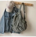 Detail of grey-green nylon backpack with ruched texture hanging on wooden hook in studio - No Pendant / Bean Green