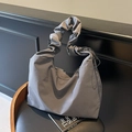 Bolso tote hobo gris oscuro con asa plisada y cordón lateral sobre una silla - Gris