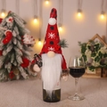 Christmas gnome wine bottle cover with red knit hat, white beard, and mini lantern - Holding Kerosene Lamp Style