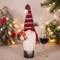Christmas wine bottle cover with knit striped gnome hat and plush beard decoration - Holding Gift Bag Style