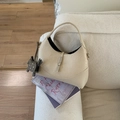 Close-up of beige moon bag with crocodile texture, silver clasp and elephant charm - Off White
