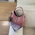 Mauve hobo shoulder bag with silver buckle on a white sofa with lifestyle props - Bubble Pink