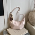 Pink crescent underarm bag with pleated design and decorative chocolate pendant - Pink