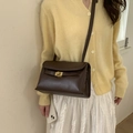 Vintage dark brown crossbody bag with metal lock detail worn with casual outfit - Brown