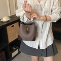 Sac seau contrasté en cuir marron avec fermoir doré et coins renforcés tenu par un modèle - Marron