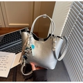Détail du sac seau argenté avec pendentif chiot et sucette bleue sur un bureau moderne - Avec Pendentif / Argent