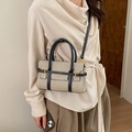 Sac bandoulière minimaliste en toile et cuir porté par un mannequin dans un cadre intérieur - Noir