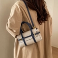 Sac à bandoulière chic en toile beige avec bordure en cuir bleu marine sur un mannequin - Bleu