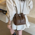 Elegante borsa a secchiello trapuntata marrone con tracolla a catena argento in scena casual - Marrone