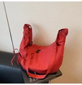 Sac croissant en nylon rouge sur un livre noir montrant la texture plissée et la sangle - Rouge