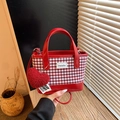 Red gingham handbag with plush heart charm and smooth red base shown in lifestyle setting - Red Small