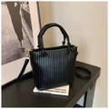 Detailed close-up of a black pleated bucket bag with a woven handle and gold hardware - Black