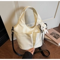 Dettaglio della borsa tote in pelle off-white con tasche laterali, tracolla nera e ciondolo - Con Ciondolo / Bianco Sporco