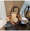 Gros plan sur le sac polochon en cuir crème avec pendentif ours et poignée brune - Avec Pendentif / Blanc Cassé