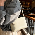 Minimalist cream shoulder bag with silver crescent hardware shown in a sunset cafe setting - White with Pendant