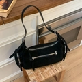 Detail of a black matte vintage shoulder bag with multiple zippers on a wooden stool - Black