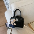 Detail of black leather handbag with silver twist lock and cute bear plush charm accessory - Black With Pendant