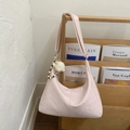 Detail of light pink wrinkled hobo bag with fluffy charm hanging on a wooden shelf - Pink
