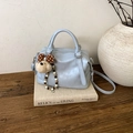 Dettaglio borsa boston azzurra vintage con ciondolo a cucciolo e sfondo di libri - Blu con Pendente