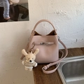 Detail der hellrosa Eimer-Tasche aus genarbtem Leder mit silbernem Schloss und Bär - Roze mit Anhänger