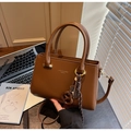Détail d'un sac à main marron rétro en cuir avec ferrures dorées et breloque abaque - Café avec Pendentif