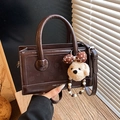 Dunkelbraune glänzende Handtasche in Kastenform mit Henkeln und Teddybär-Anhänger - Mit Anhänger / Braun