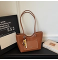 Detalle de un bolso tote de cuero marrón con grabado de lichi y un colgante decorativo de cuentas - Marrón