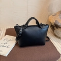 Detail view of black leather Boston bag with silver buckle and adjustable shoulder strap - Black